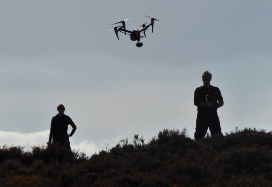 Silhouette of two people flying a drone