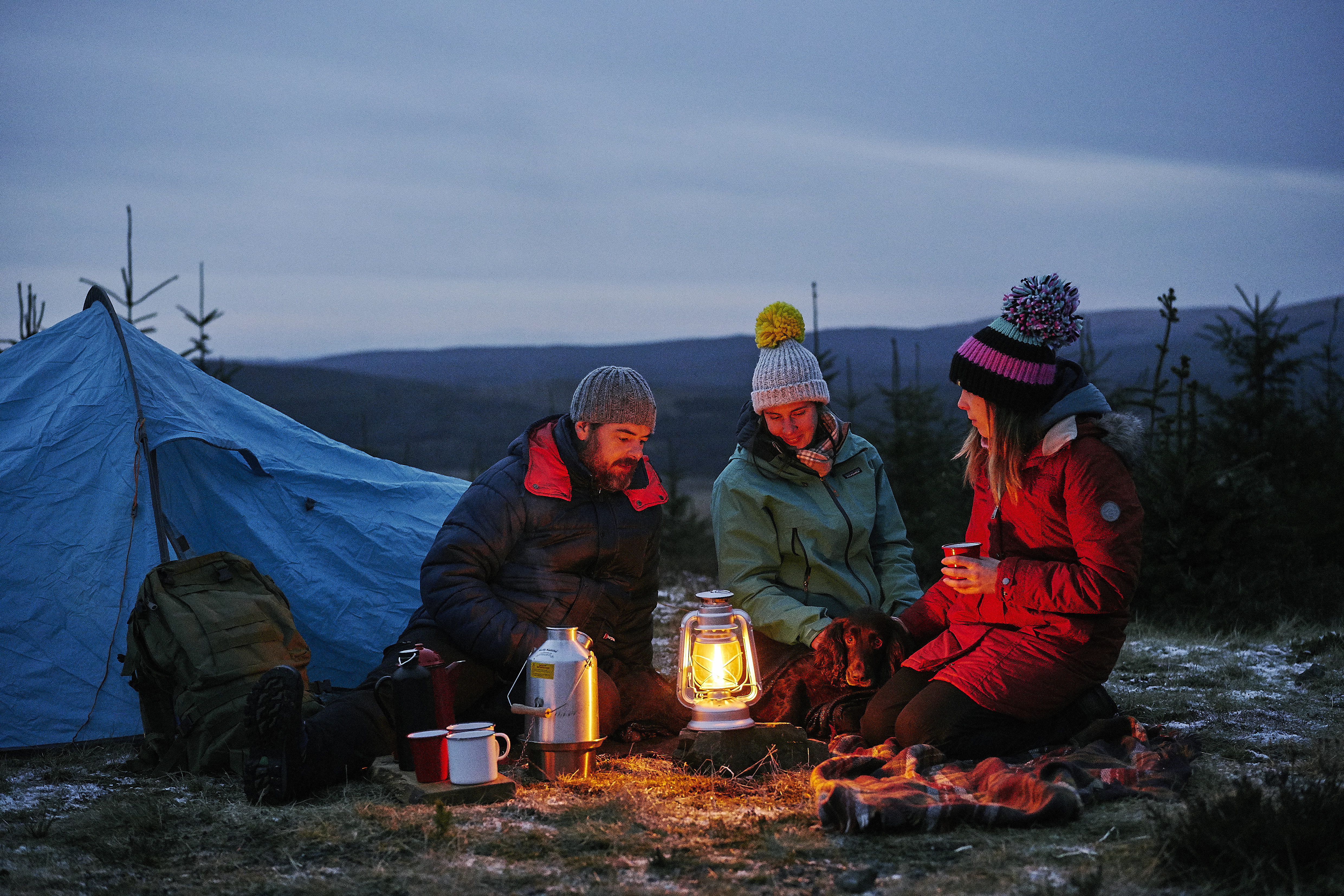 Three friends camping under the night sky