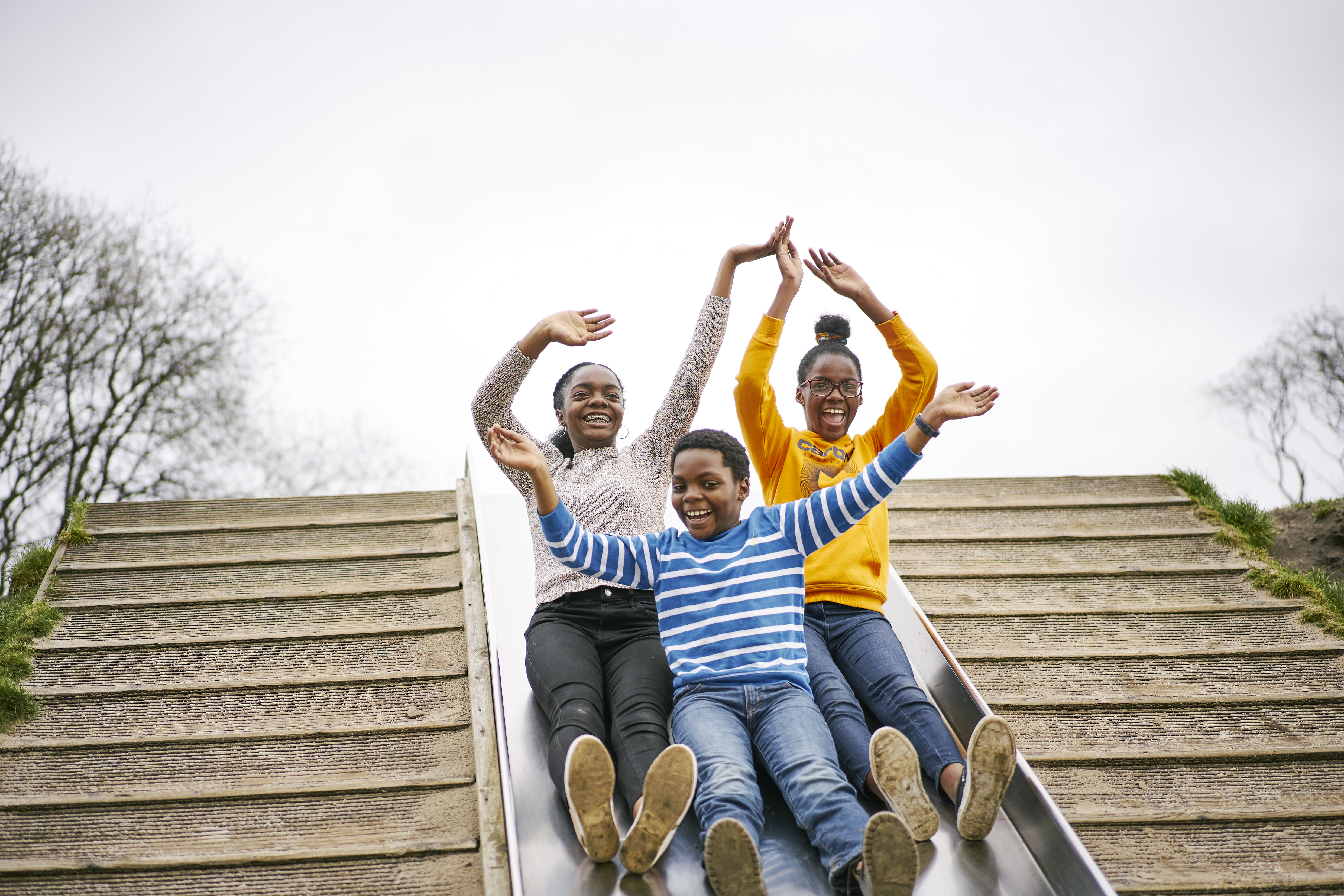 Three children going down a large playpark slide
