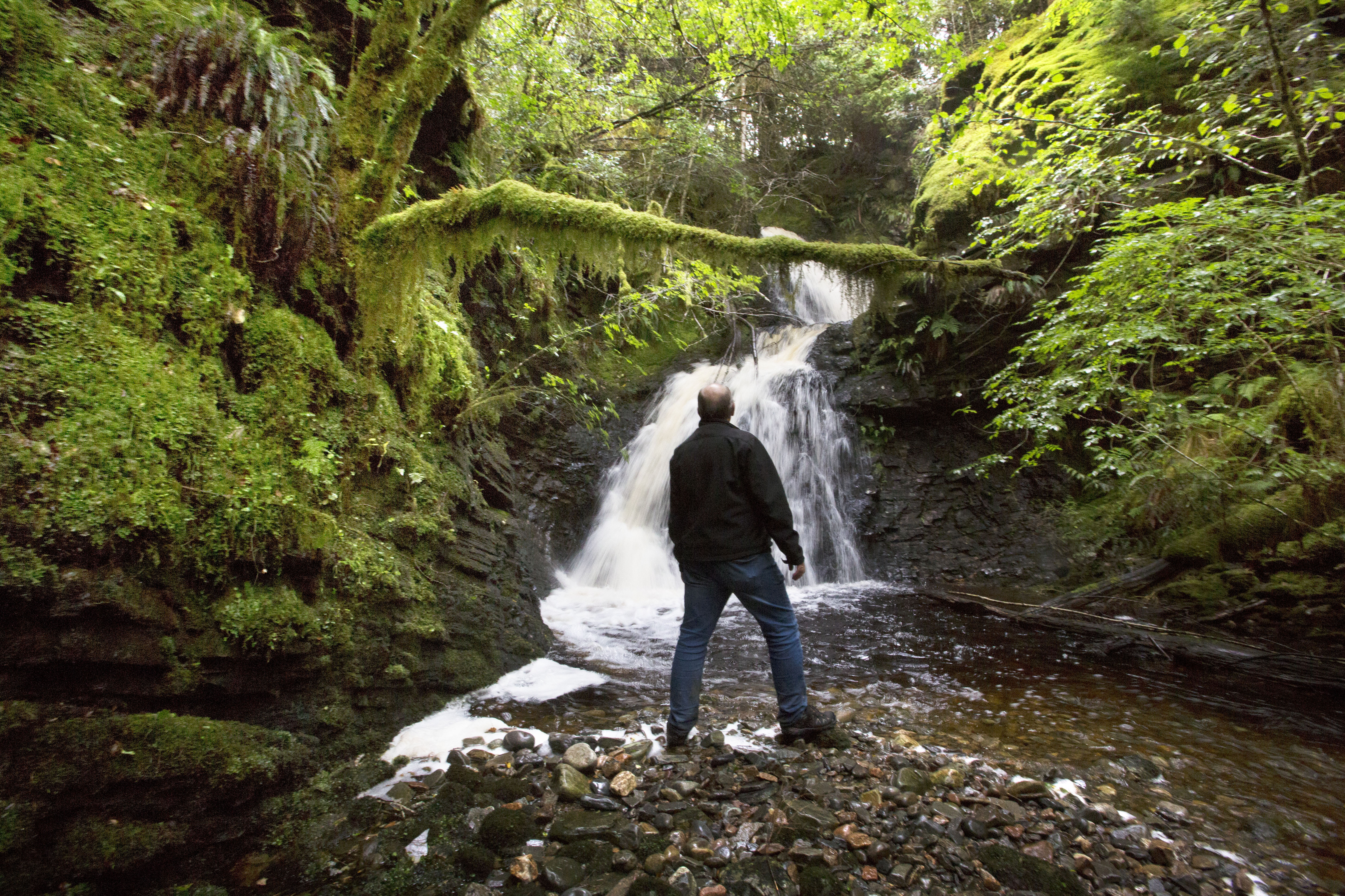 Man standing in front of waterfall at Allt na Criche