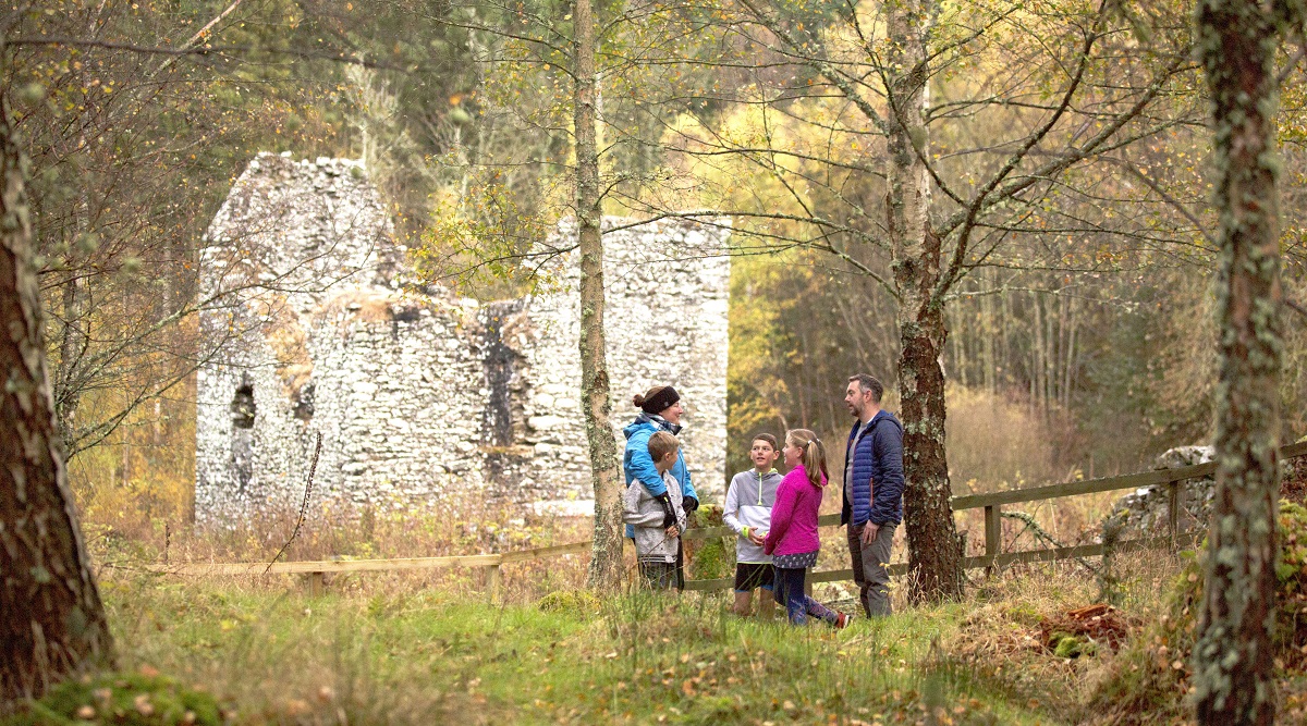 A family standing in front of the ruins of Cardrona Tower