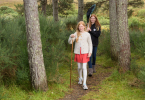 Two young girls walk through forest, carrying fishing net, Borgie Breco, Borgie, Sutherland