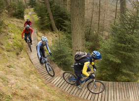A group of mountain bikers riding along a wooden boardwalk