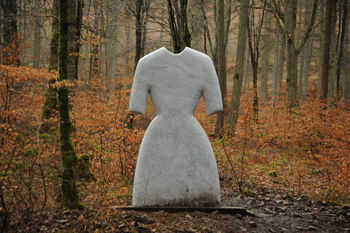 A large granite sculpture of a woman's dress in a autumn forest