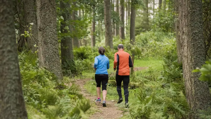 Two people running through a woodland.
