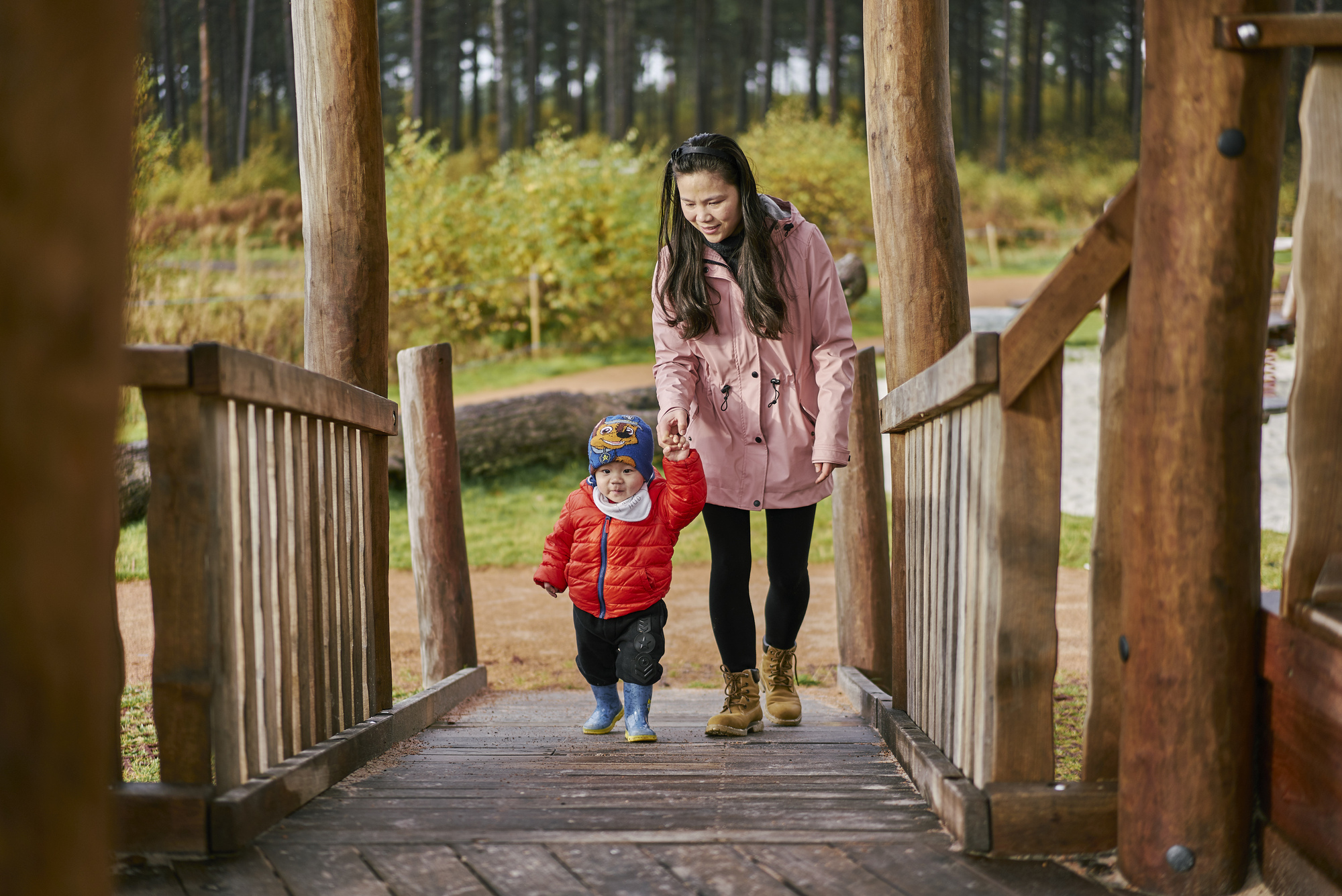 Woman and young boy walking across wooden bridge at Tentsmuir (near Leuchars) on forest trail