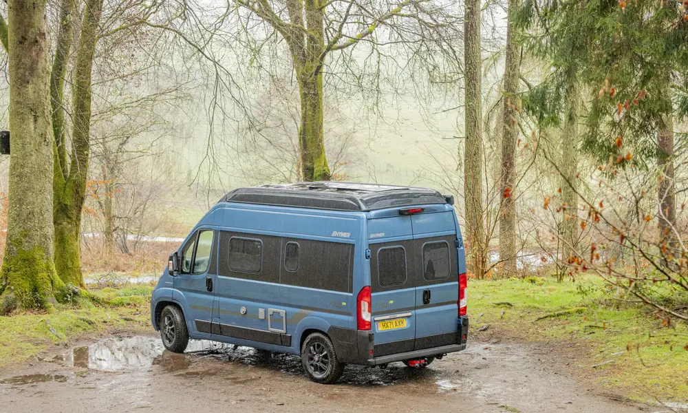 A blue camper van parked in a forest