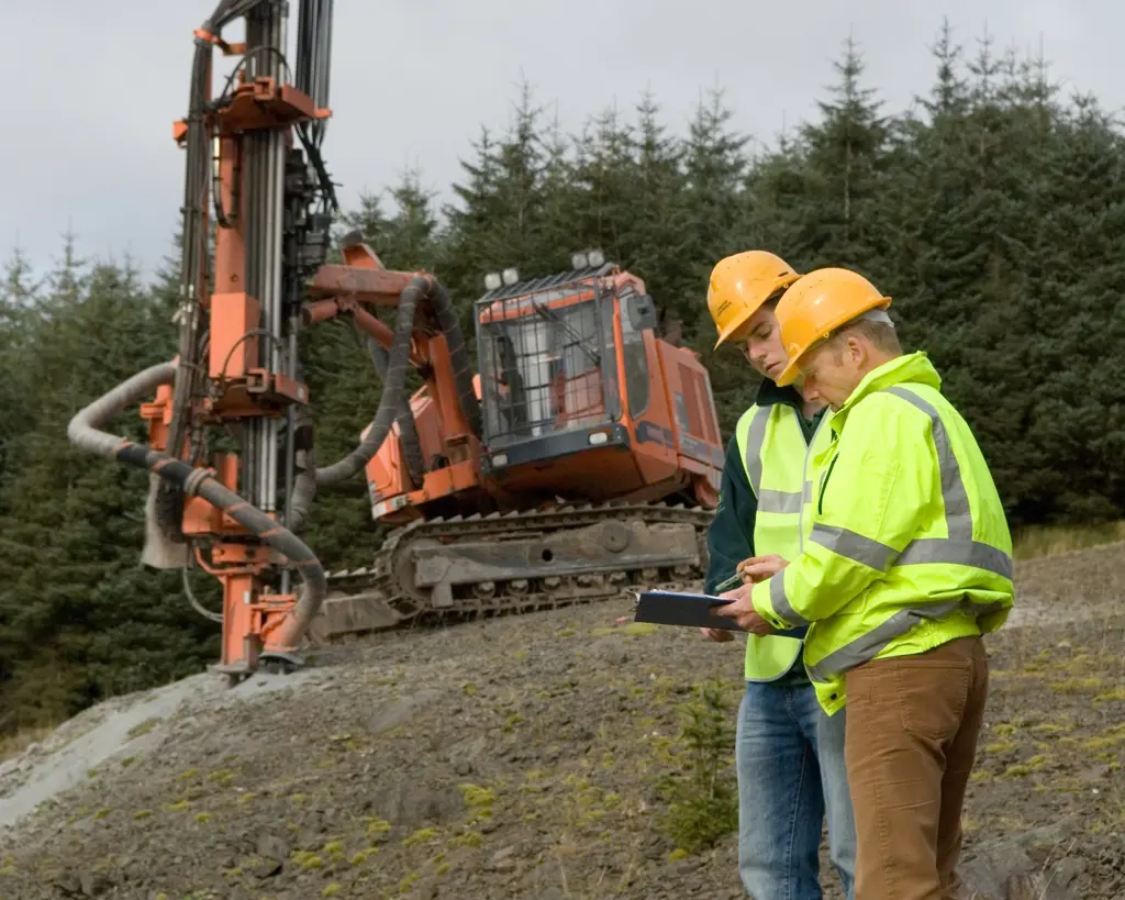 Two people in the foreground with a machine in the background.