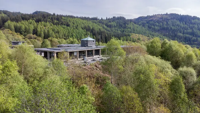 An aerial shot of a building through trees with hills behind