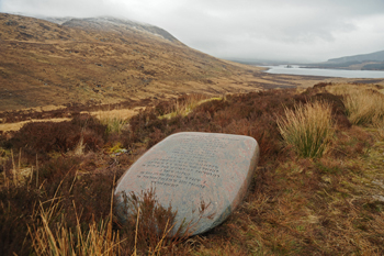 A giant axe like boulder sits in the hillside with runic letters carved into it