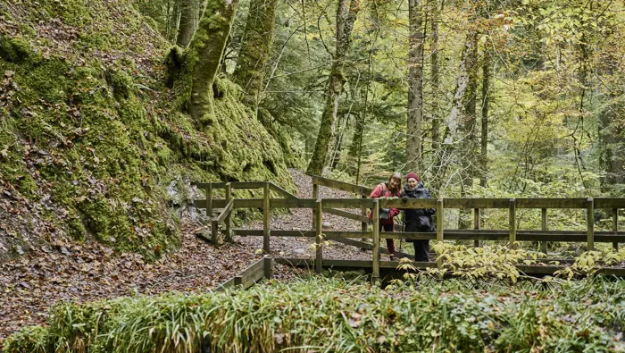 Two people looking out from a small bridge.