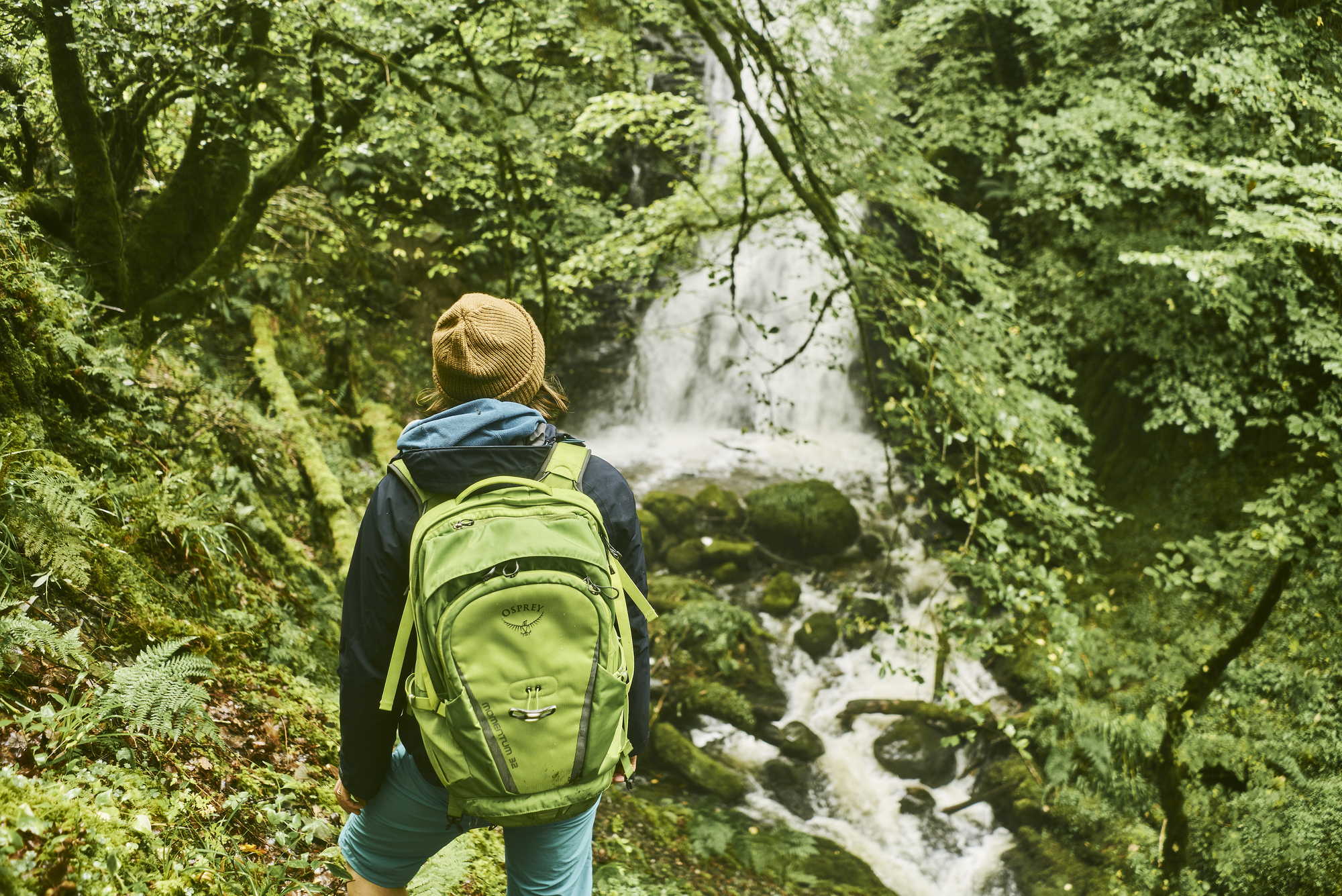  Young woman hiker carrying haversack views waterfall, Glen Creran, near Glencoe