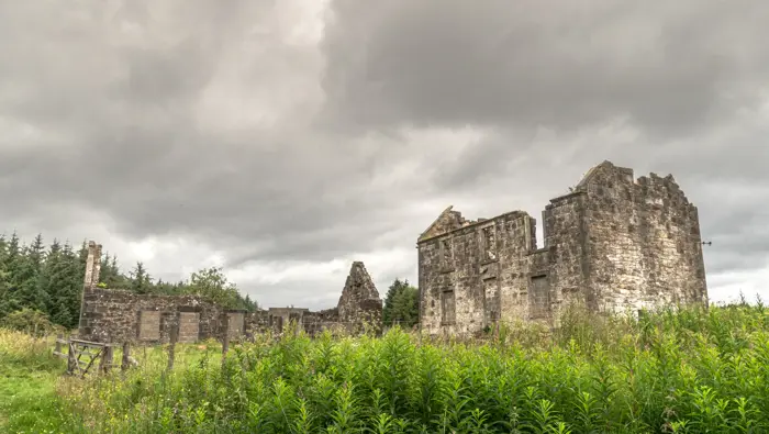  Old stone buildings in a field with trees behind