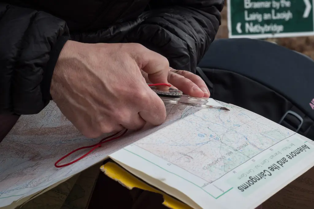 Detail of hiker's hands looking at map with compass, Ryvoan, Glenmore Forest Park , near Aviemore