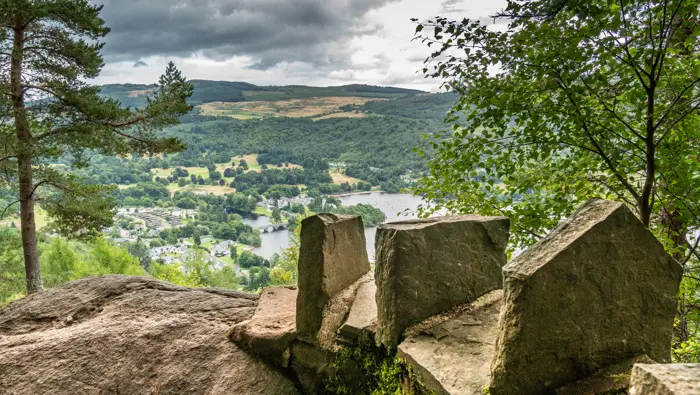 Viewpoint over a loch with a wall and trees in the foreground.