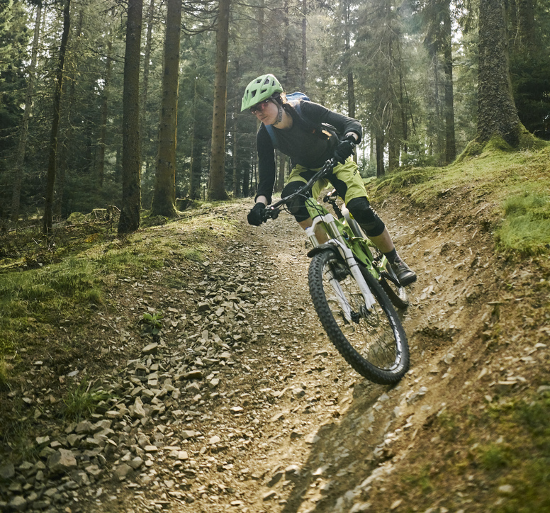 A woman riding a bike down a gravel trail