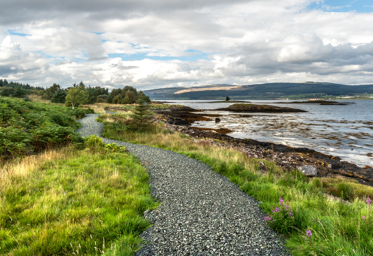 A gravel path next to the sea with an island