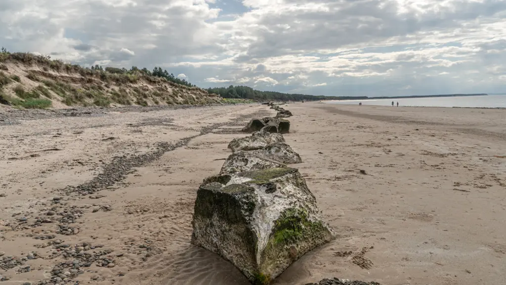 View of a beach with large concrete structures on it.