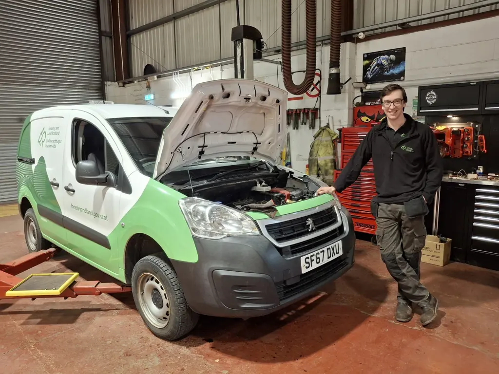 Mechanic standing next to van in a workshop.