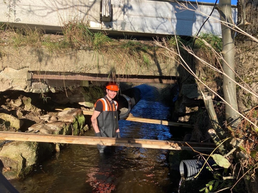 Andrew in a stream under a bridge.