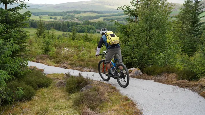 Mountain biker on a trail with hills in the background.