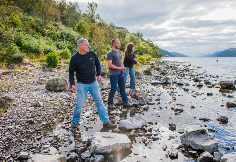 Two men and a woman skimming stones on south side shore of Loch Ness, near Change House