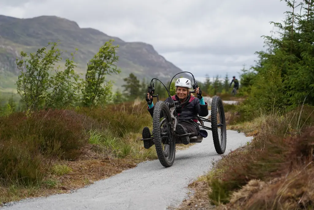 Rider on an adaptive bike with a rider on a mountain bike in the background.