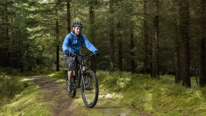 Person in blue jacket on mountain bike.