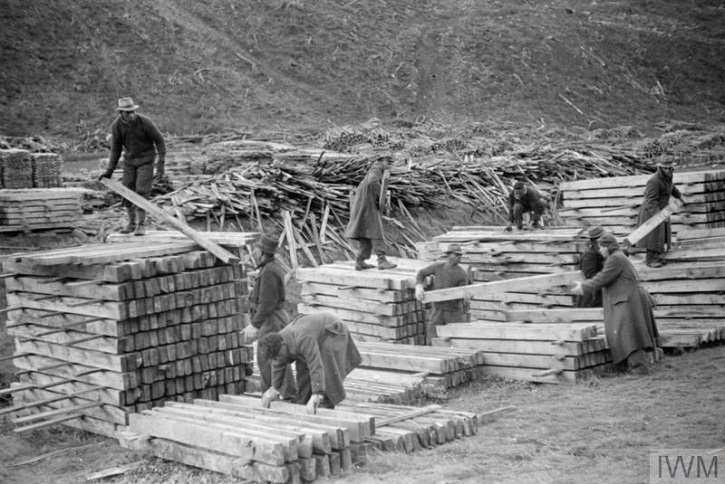 Black and white image of foresters stacking timber.